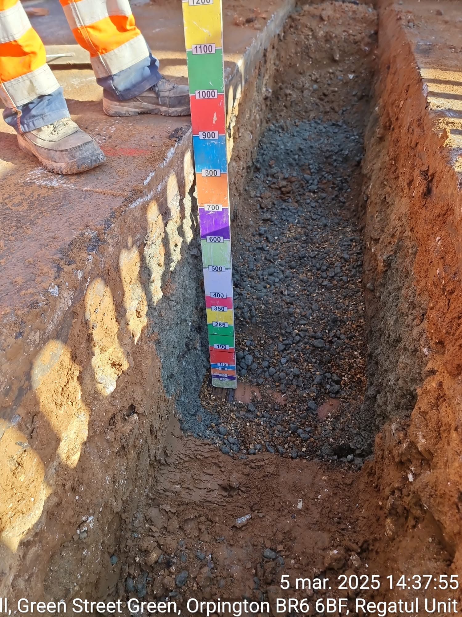 Excavated trench with a depth staff beside the cut